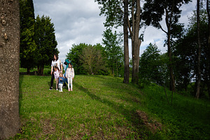 Family walking together in a lush green park on a sunny day, a Person Photo by AS photostudio