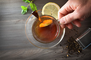 Person holding a cup of hot tea on dark table, a Food & Drink Photo by Davizro's Market