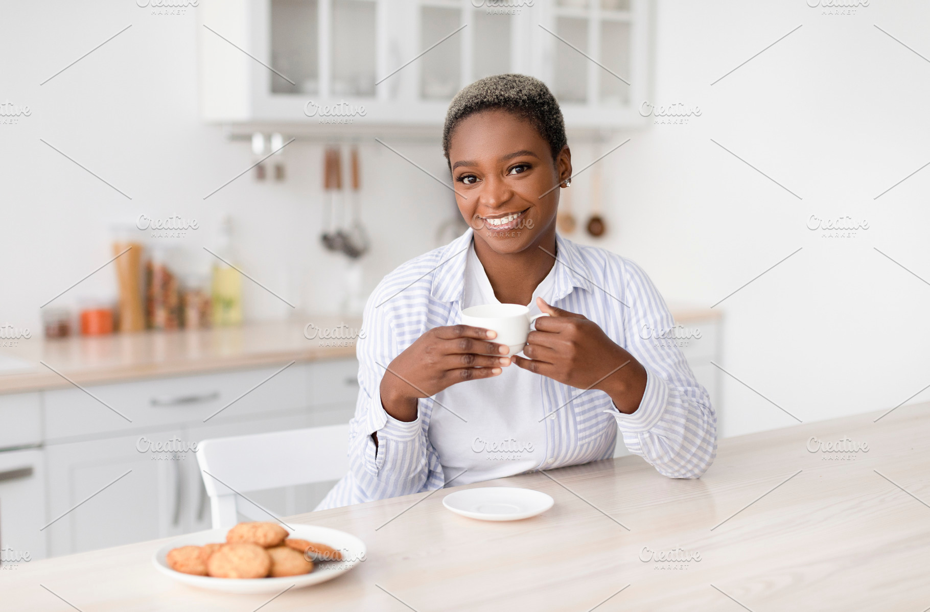 Smiling young african american woman with cup of coffee in hands drinks favorit, a Person Photo by Prostock-Studio