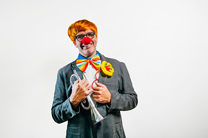 Smiling clown holding trumpet ready for performance, a Person Photo by karrastock