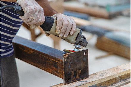A man processes a metal pole, an Industrial Photo by yanadjana