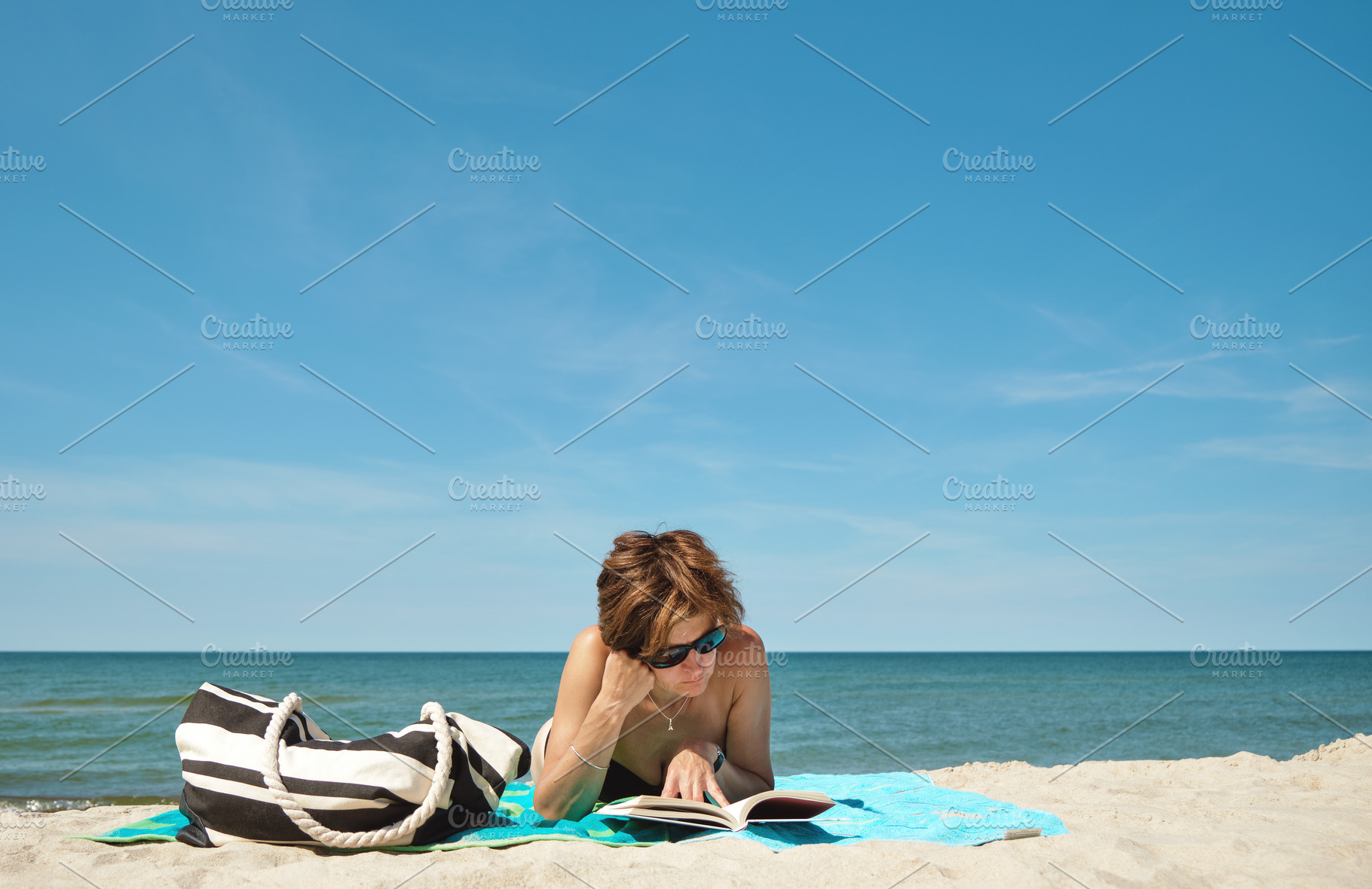 Woman reading a book on the beach, a Person Photo by BOOCYS