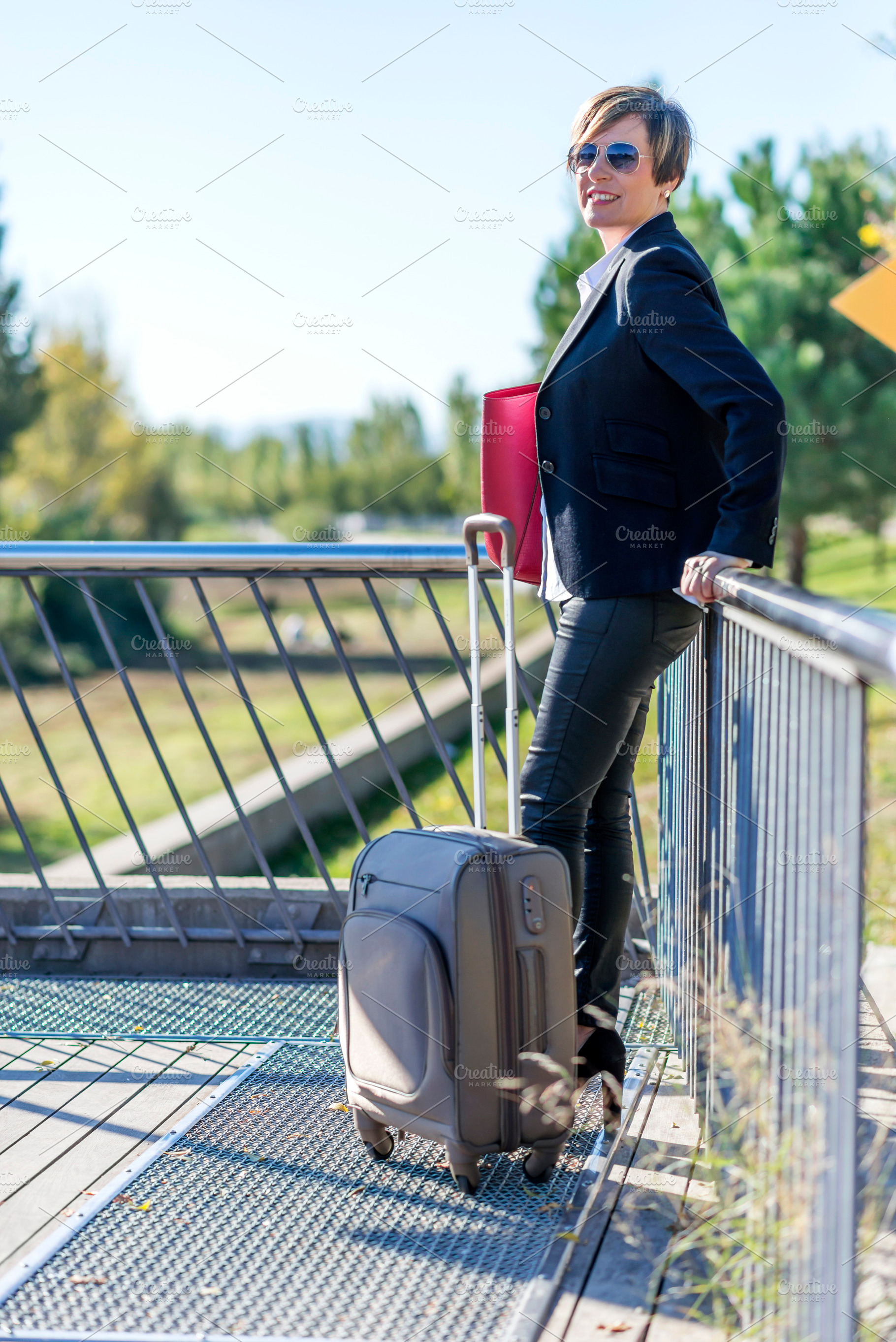 Businesswoman with suitcase standing on bridge, a Photo by RF Images