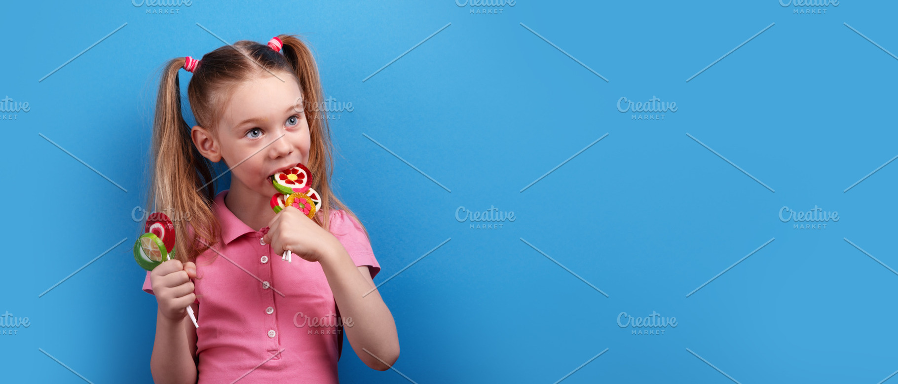 Happy girl in a pink shirt playfully biting into a bunch of colo, a Person Photo by Ales Munt