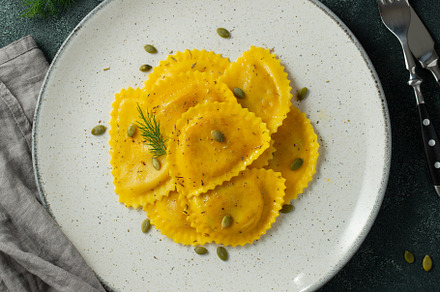 Homemade Pumpkin Ravioli with butter on a dark concrete background. Top view, a Food & Drink Photo by Budarinphoto