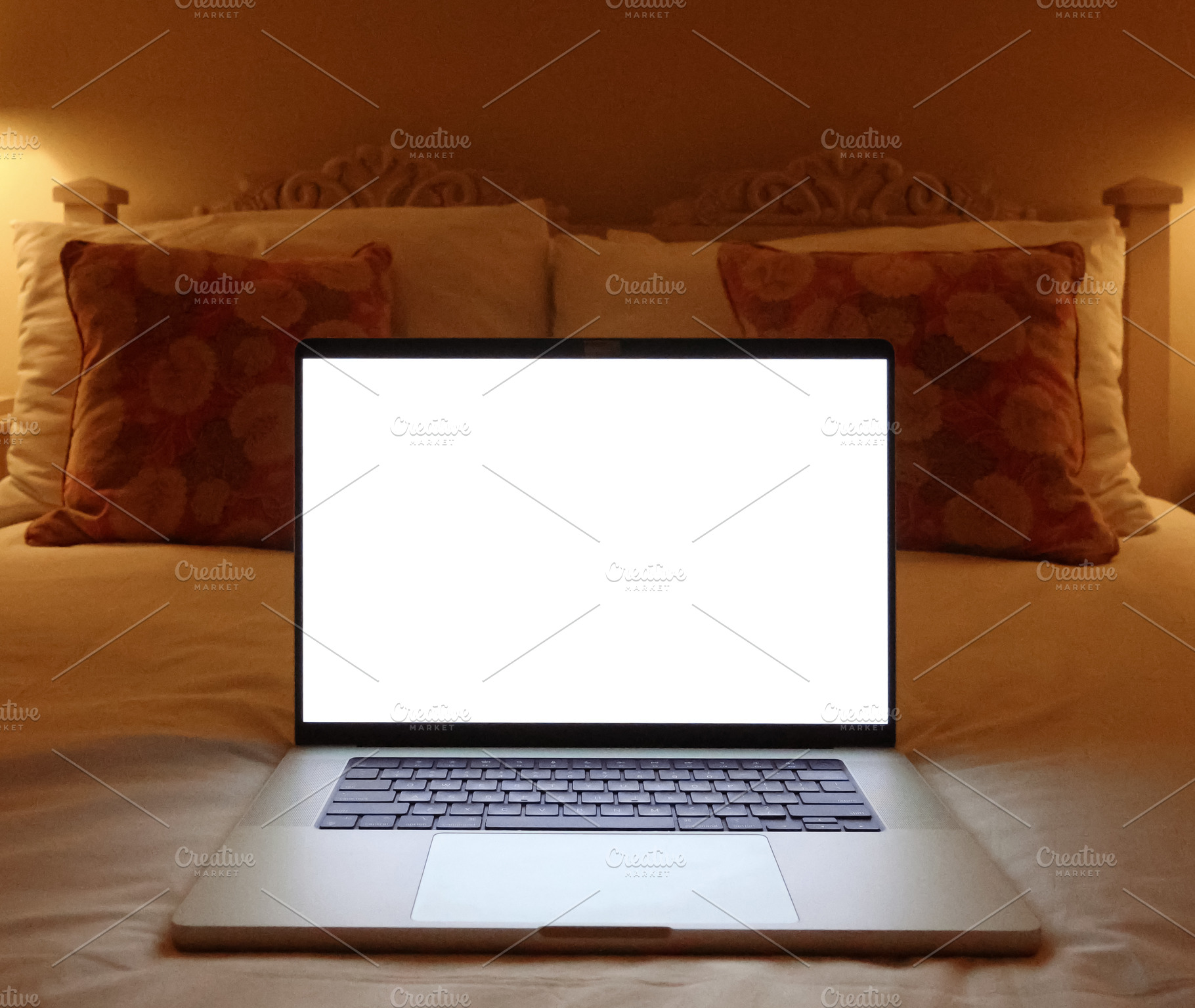 Laptop with blank white screen on a bed, lit by lamps, representing remote work, a Photo by Studio ANNA