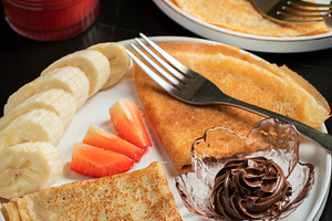 A plate of crepes filled with chocolate spread and topped with b, a Food & Drink Photo by Budarinphoto