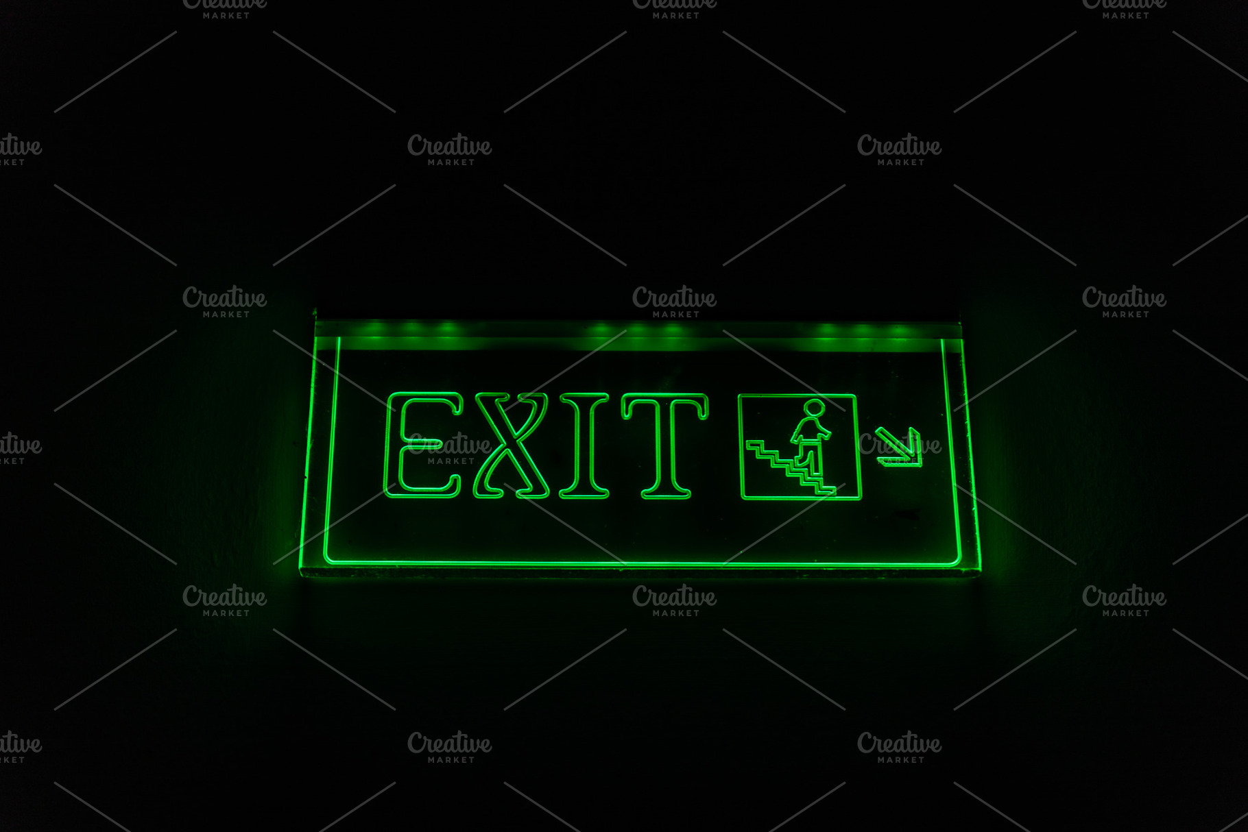 Bright green exit sign glowing in darkness, highlighting emergency stairs for s, an Abstract Photo by Ales Munt