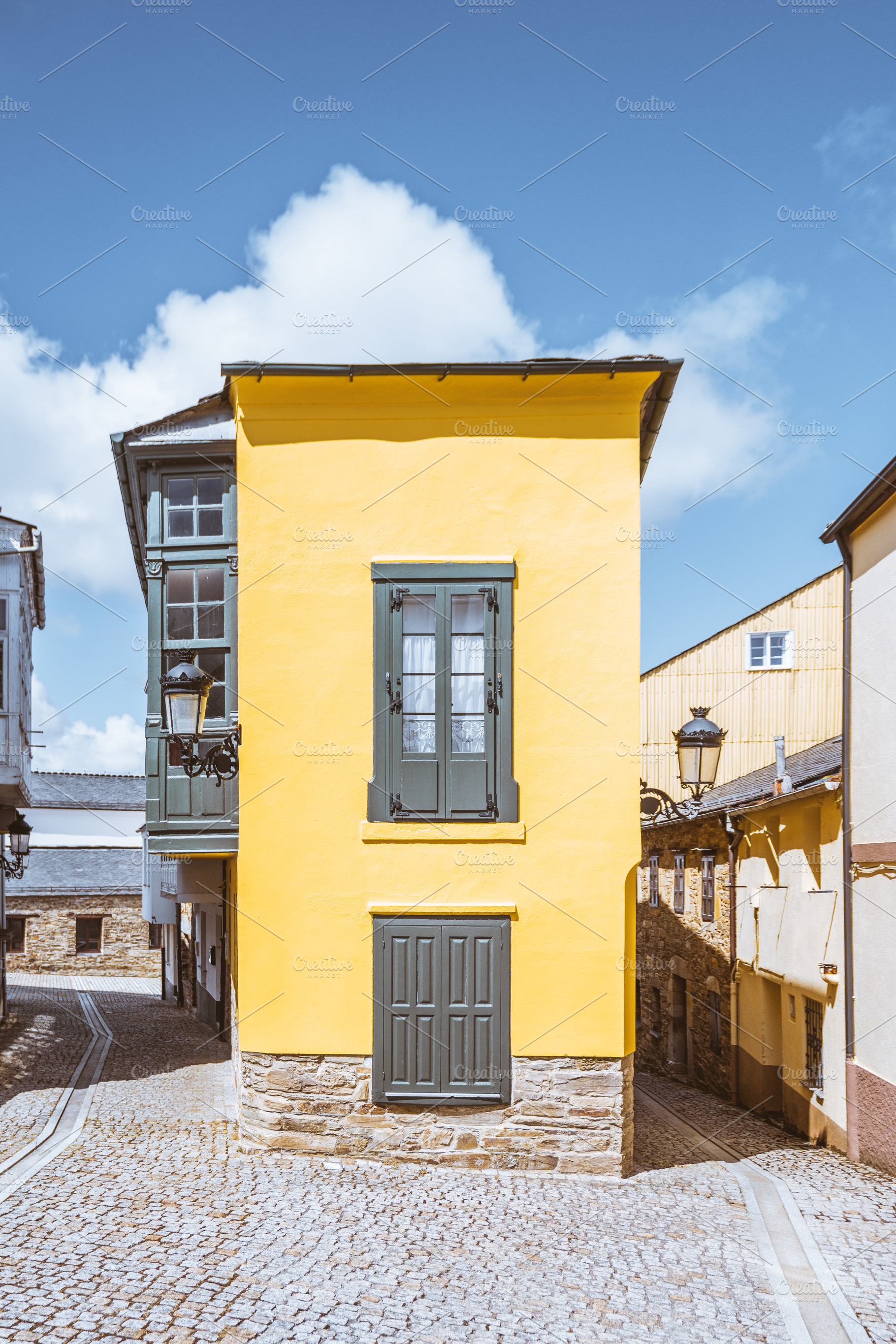 Yellow house on cobblestone street, an Architecture Photo by SkyNext