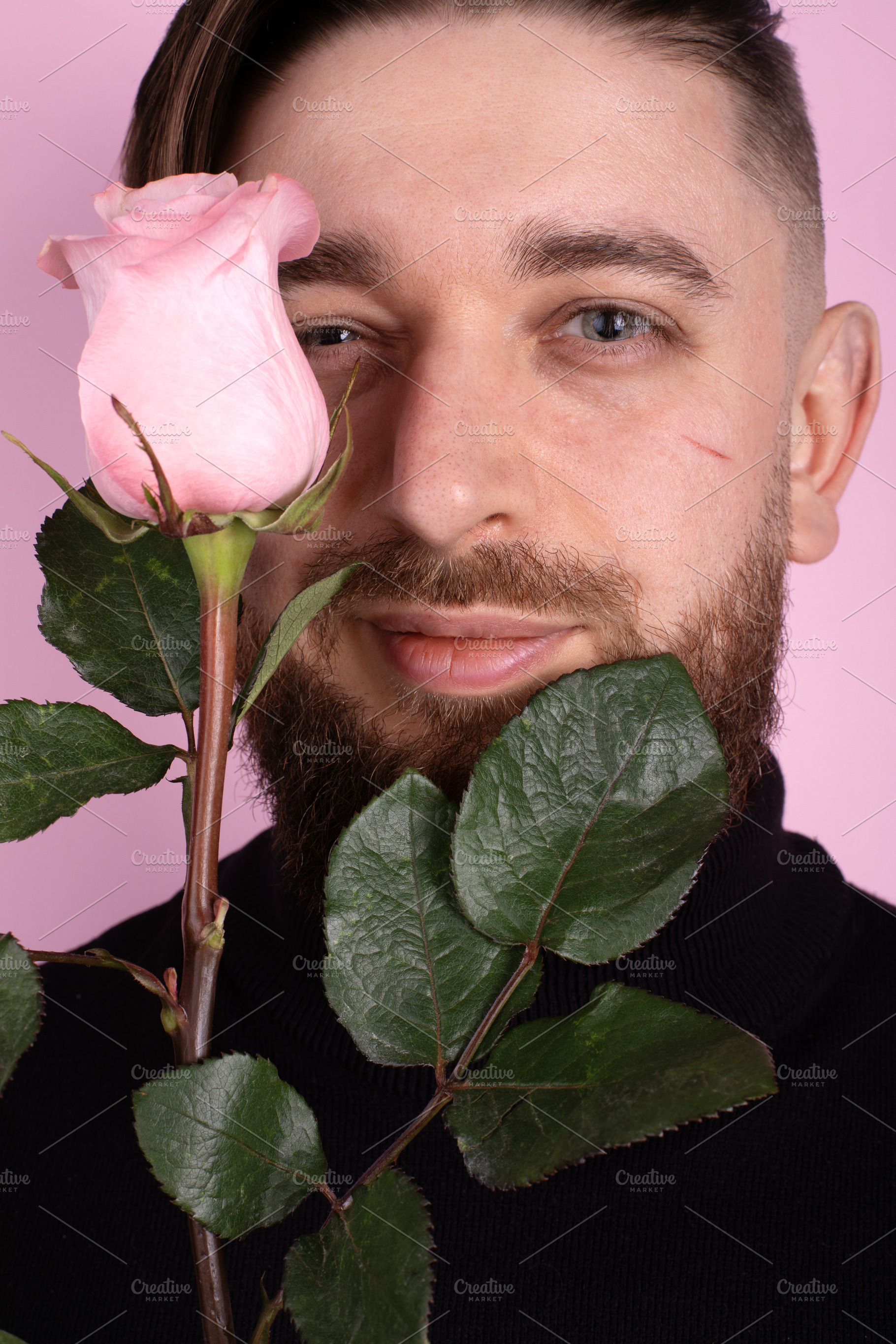Close-up of a bearded man holding a pink rose in front of his fa, a Person Photo by Ales Munt