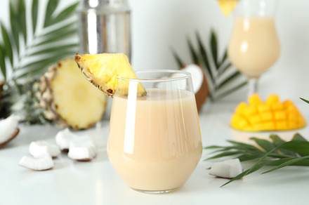 Pina colada cocktail and ingredients on white table, a Food & Drink Photo by AtlasStudio