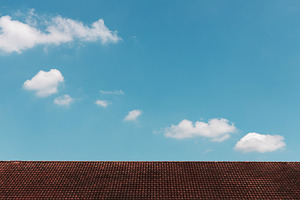 Clouds in the Blue Sky on Sunny Day over Red rooftop, a Photo by salmon.black