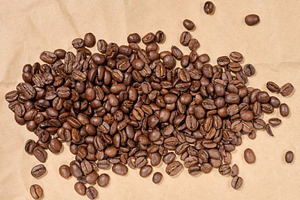 Scattered roasted coffee beans on brown paper, a Food & Drink Photo by ndanko