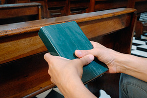 man holding a green prayer book in church, a Photo by Nito