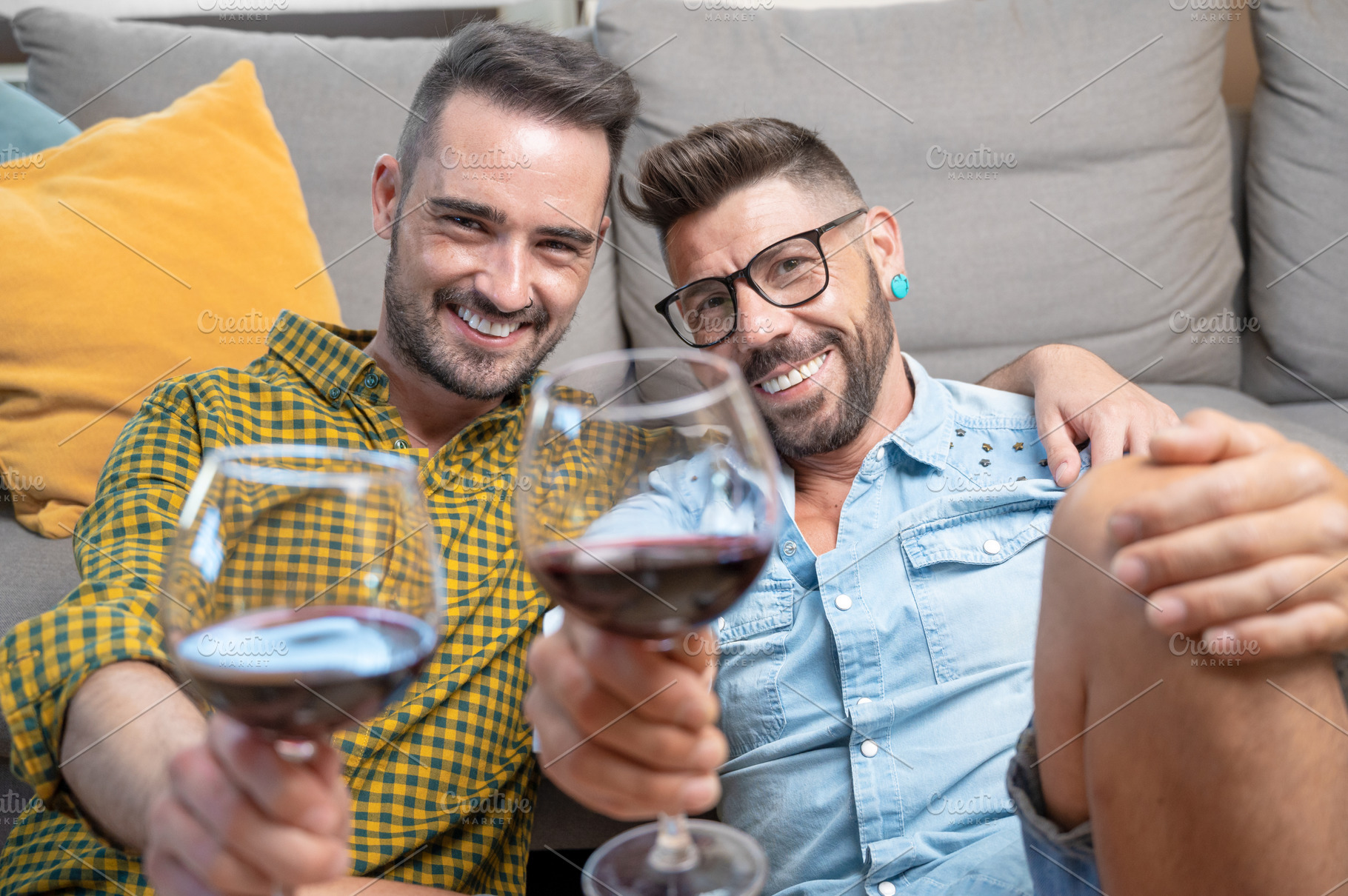Gay couple in love sitting at home on the floor and toasting with red wine., a Person Photo by david.herraez.calzad