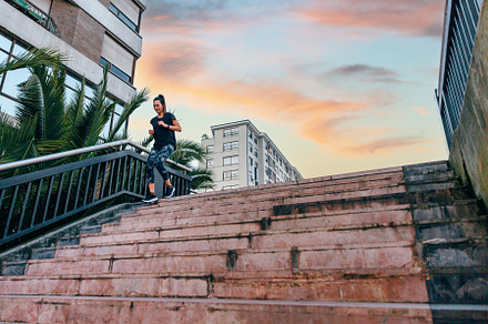 Female runner training down stairs over in urban runway on sunse