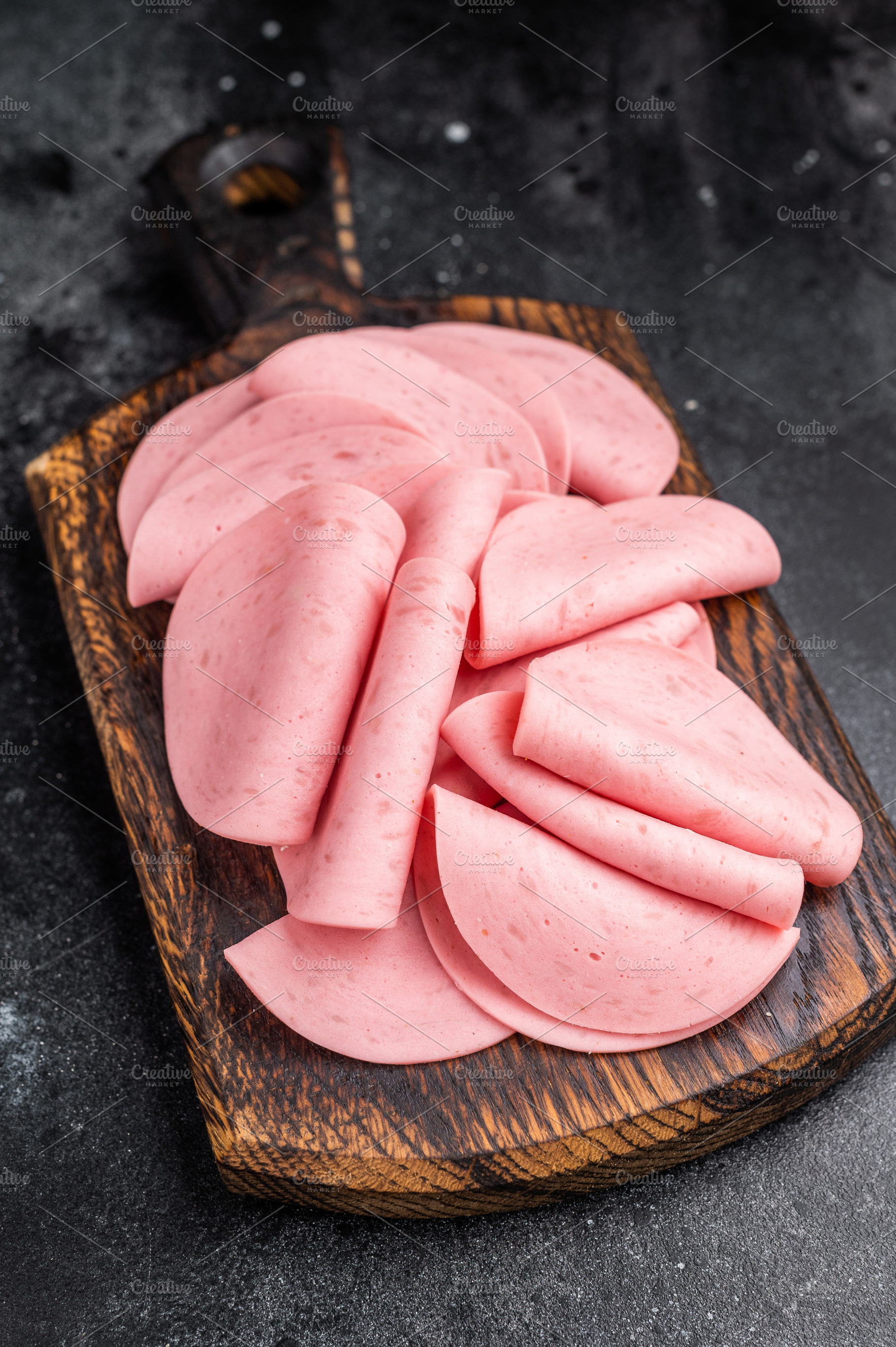 Overhead view of cold cuts (mortadella) on a small wooden board., a Food & Drink Photo by composter-box@mail.ru