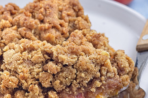 Peach Crisp or cobbler with brown sugar and oat streusel on plate, vertical, cl, a Food & Drink Photo by iuliia_n