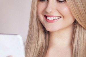 Young woman smiling while looking at a mobile phone, showing healthy teeth, nat, a Person Photo by Studio ANNA