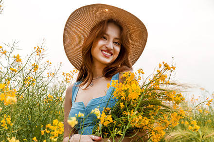 The girl holds in her hands a bouquet of rapeseed and spikelets of wheat, a Person Photo by Photostock