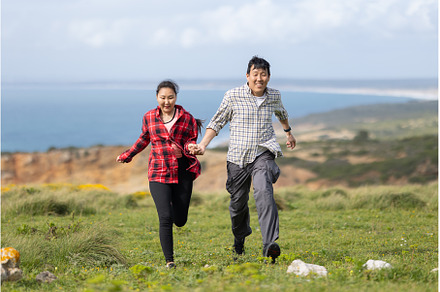 A couple running on a grassy hill
