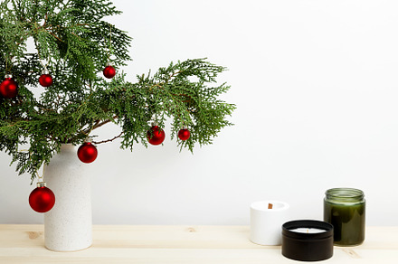 Vase with thuja branches, Christmas ornaments, pinecone, and candle for festive, a Photo by matucha