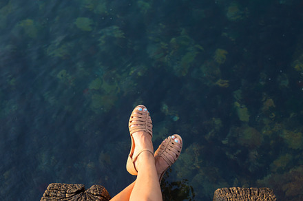 Feet of a girl who sits on a pier, a Person Photo by Artsaba Family