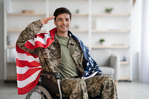 Patriotic veteran sitting in wheelchair with flag of the US, a Photo by Prostock-Studio