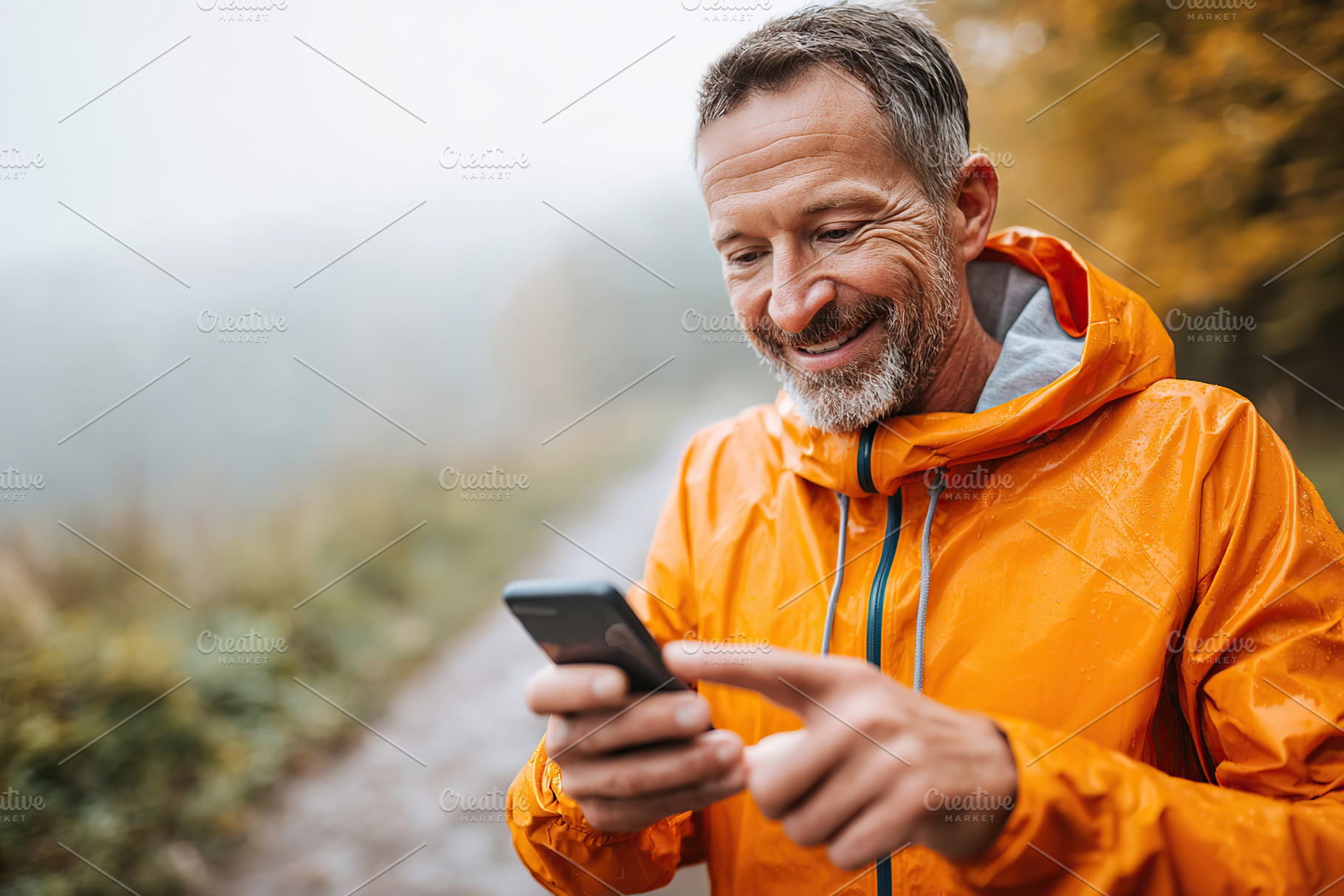 Man enjoying nature while checking his smartphone on a foggy autumn day, a Person Photo by AlyaAnd