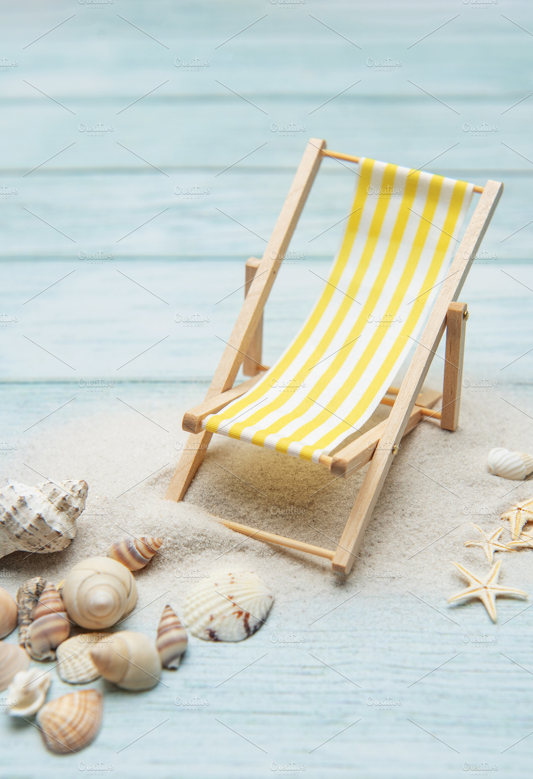 Miniature deck chair on sandy beach with seashells inviting rela, a Holiday Photo by Olena Rudo