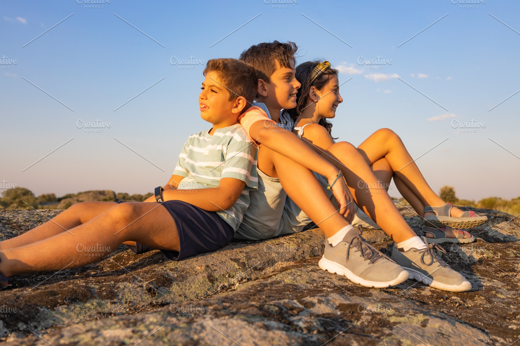 Three  kids  with on a top of a rock on their summer vacation, a Person Photo by Cosca