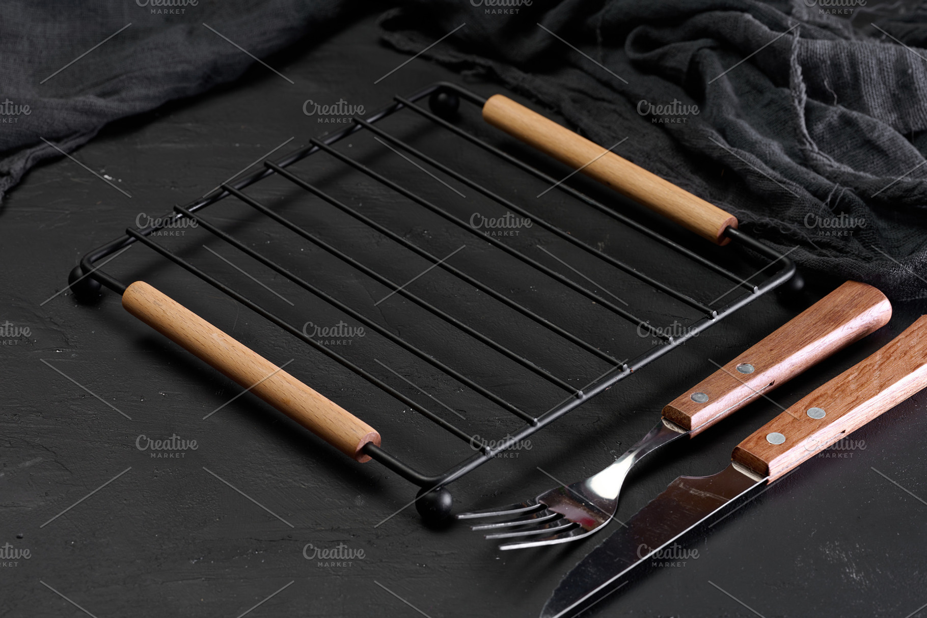 Empty metal grill grate with knife and fork on dark background, a Food & Drink Photo by ndanko
