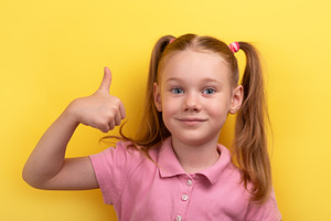 Cheerful young girl in pink shirt giving thumbs up gesture again, a Person Photo by Ales Munt