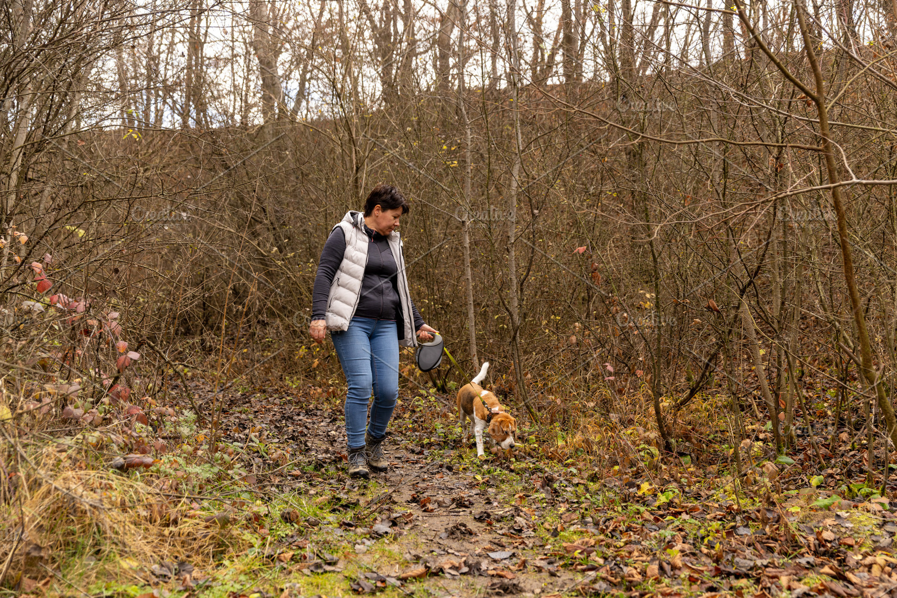 Woman and beagle walking on a muddy path, a Photo by Grafvision photography