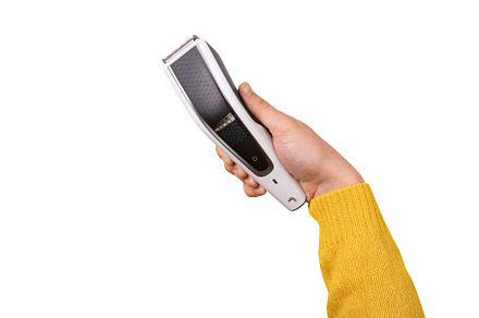 hand holding an electric hair clipper in angled position on whit