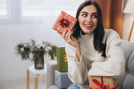 Beautiful happy woman unwrapping New Year or Christmas presents