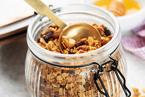 Granola cereal with nuts in a glass jar and spoon, healthy break, a Food & Drink Photo by Olena Rudo