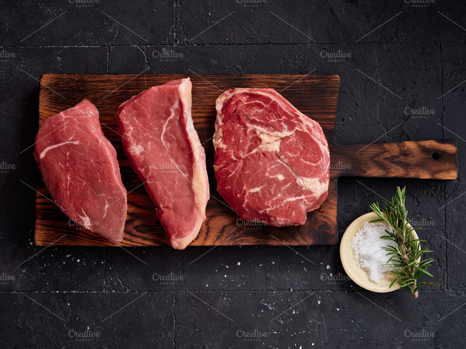 Raw rib-eye, roast beef, flank and rump steak are displayed on a wooden cutting, a Food & Drink Photo by Asya Nurullina