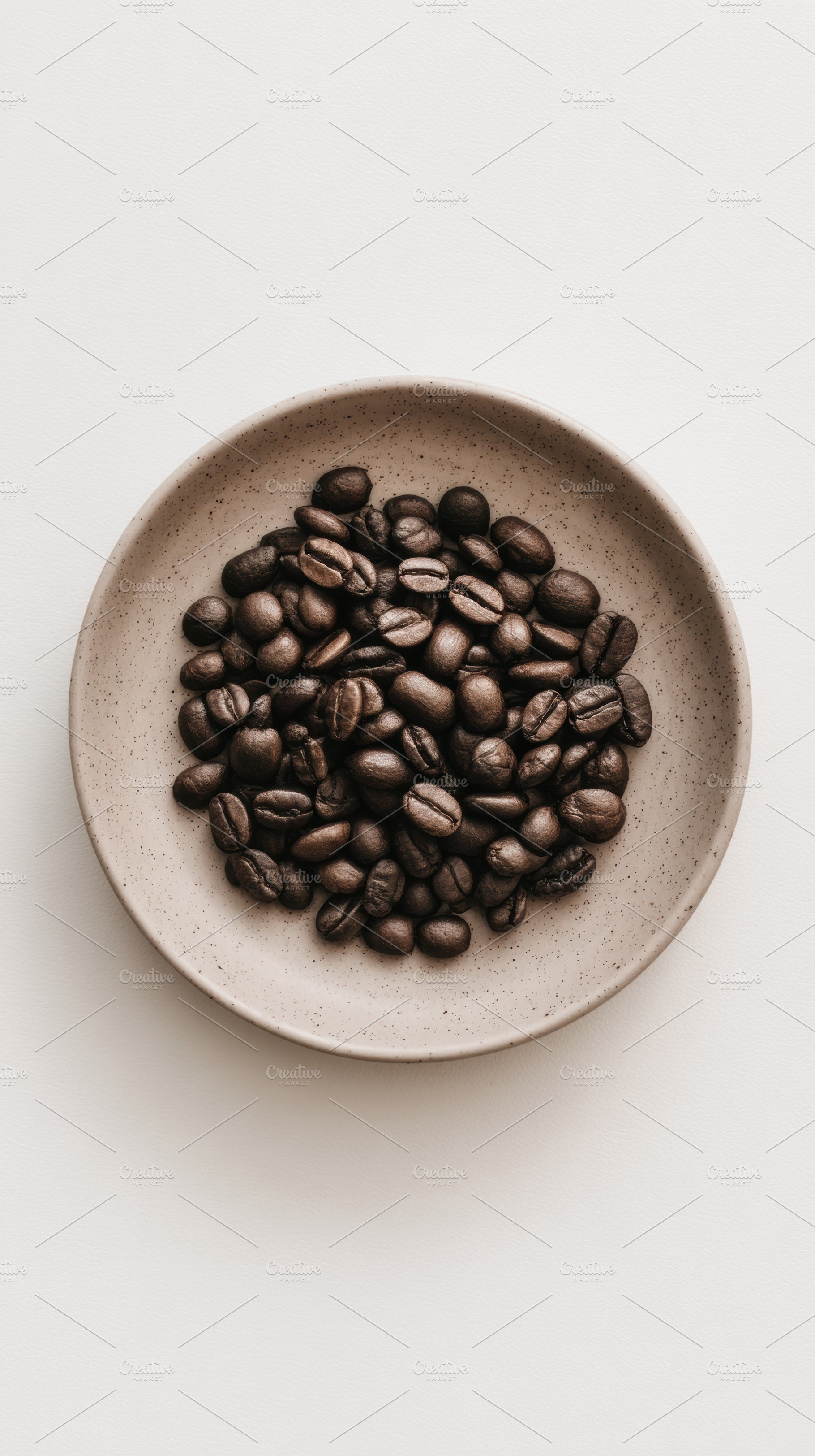 Coffee beans on white plate, a Photo by Virgo Studio