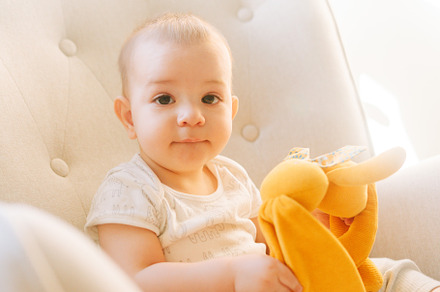 Portrait of a nine month old baby with a stuffed bunny sitting in a rocking cha