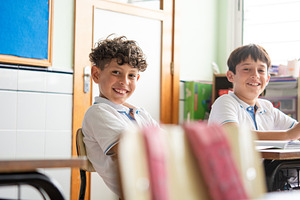 Smiling Elementary School Boys Sitting in Classroom During Lesson, a School & Education Photo by etorres69