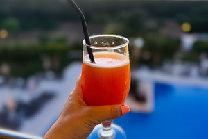 Refreshing cocktail held against scenic sunset view in Algarve, Portugal, a Photo by AS photostudio