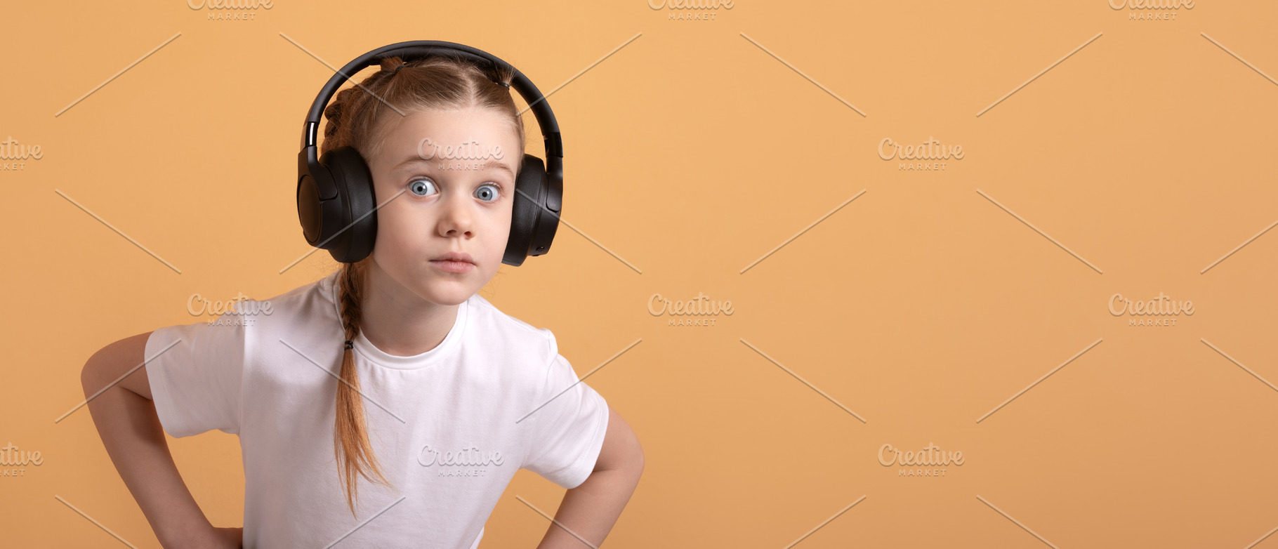 Young girl in white t-shirt wearing large headphones, looking su, a Person Photo by Ales Munt
