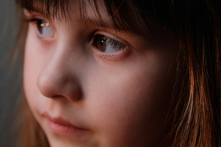Softly lit portrait focusing on the child's delicate features and side view.
