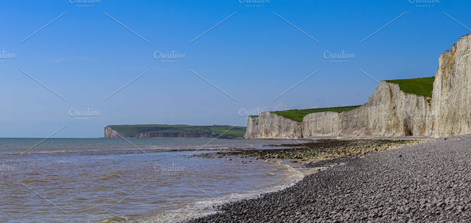 Seven Sisters cliffs towering over the pebble beach and incoming tide in East S, a Photo by Studio ANNA