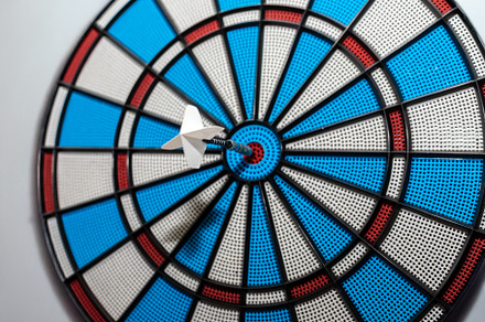 Close-up of a white dart perfectly hitting the bullseye on a col