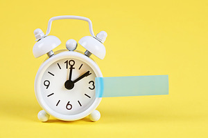 White alarm clock yellow pastel back containing alarm, clock, and white