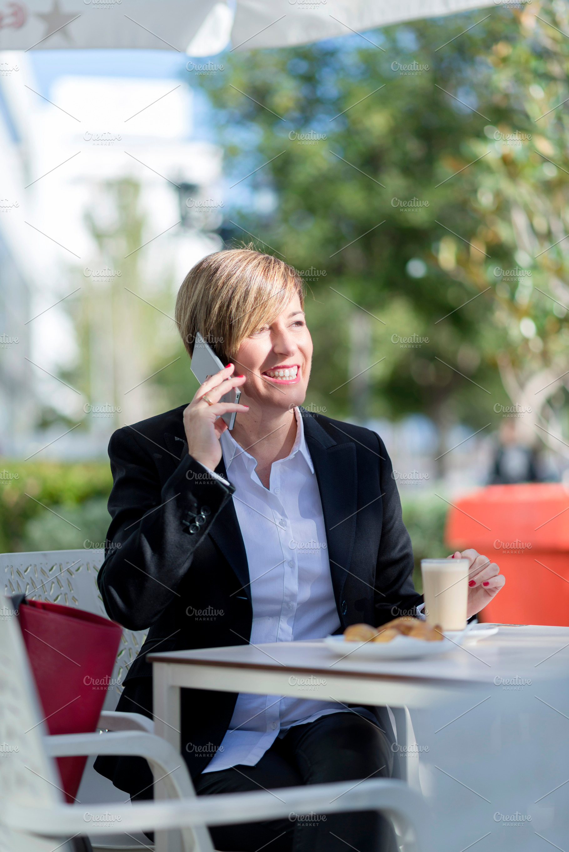 Businesswoman having coffee and phone call outdoors, a Photo by RF Images