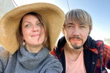 Smiling man and woman taking a close-up selfie under clear blue