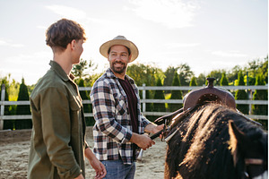 ather and son preparing horse for, a Person Photo by HalfPoint